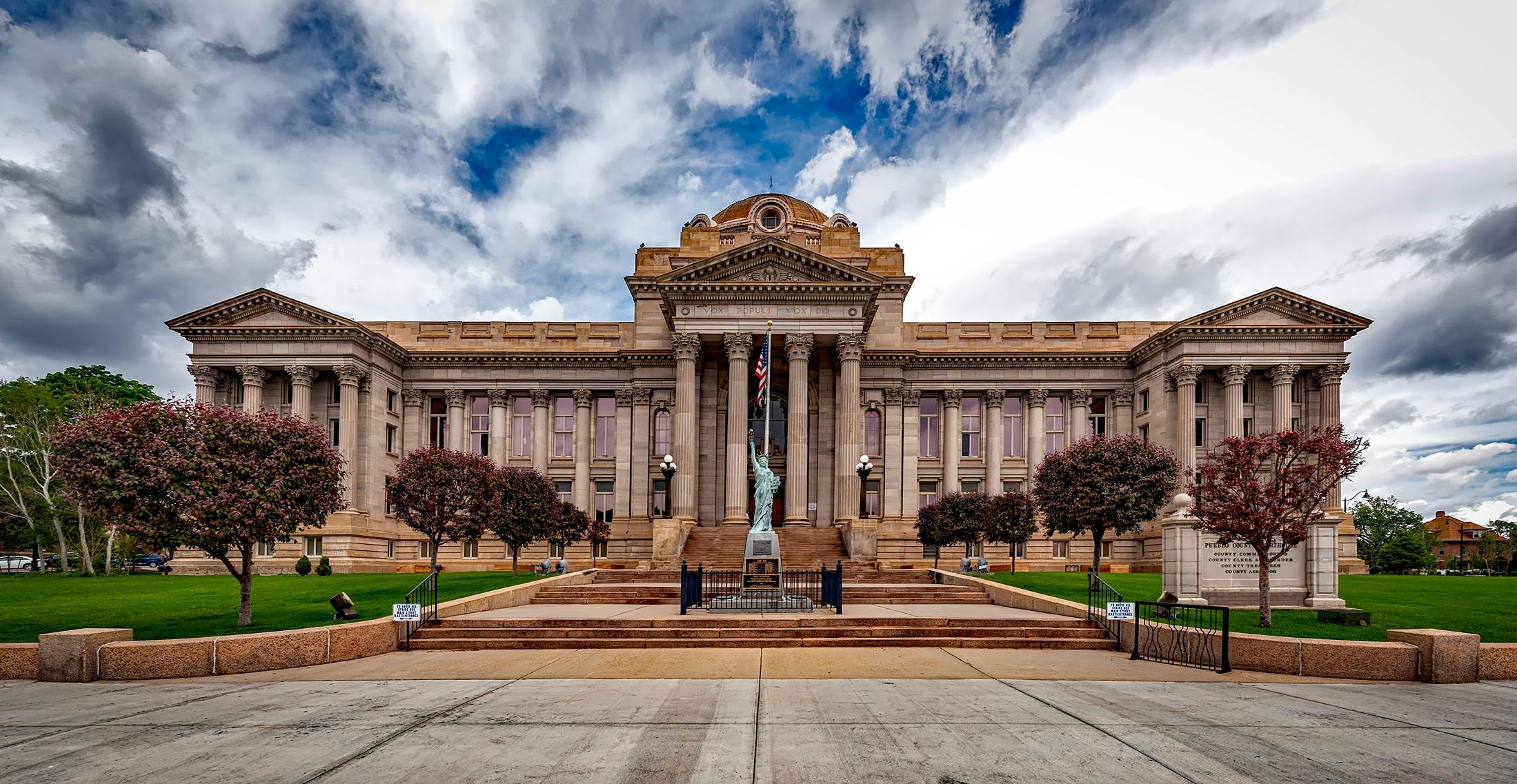 Front view of a neoclassical courthouse building in Colorado with lush greenery.